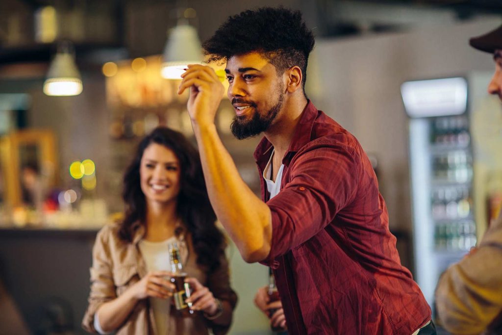 Friends playing darts and drinking beer