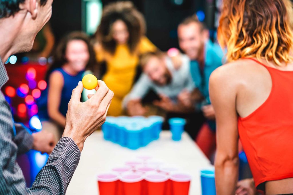 Friends playing beer pong at a party